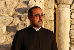 A Palestinian priest stands in a ruin