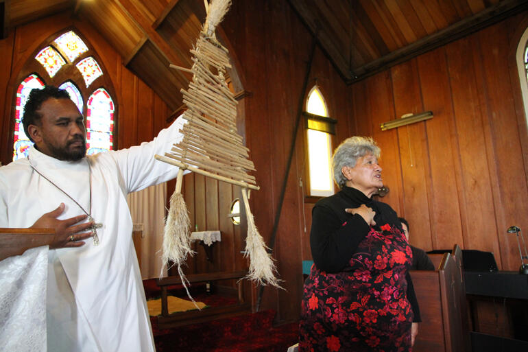 Adam Hape holds aloft an example of raupo reed construction, as Hazel Coromandel-Wander tells the story of the Rangiaowhia massacre.