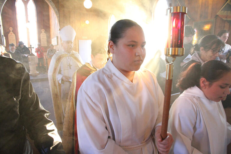 Light fills the nave of St John's Te Awamutu as Ataahua Jean Karauti-Fox carries a candle in the procession for Evensong and Benediction.